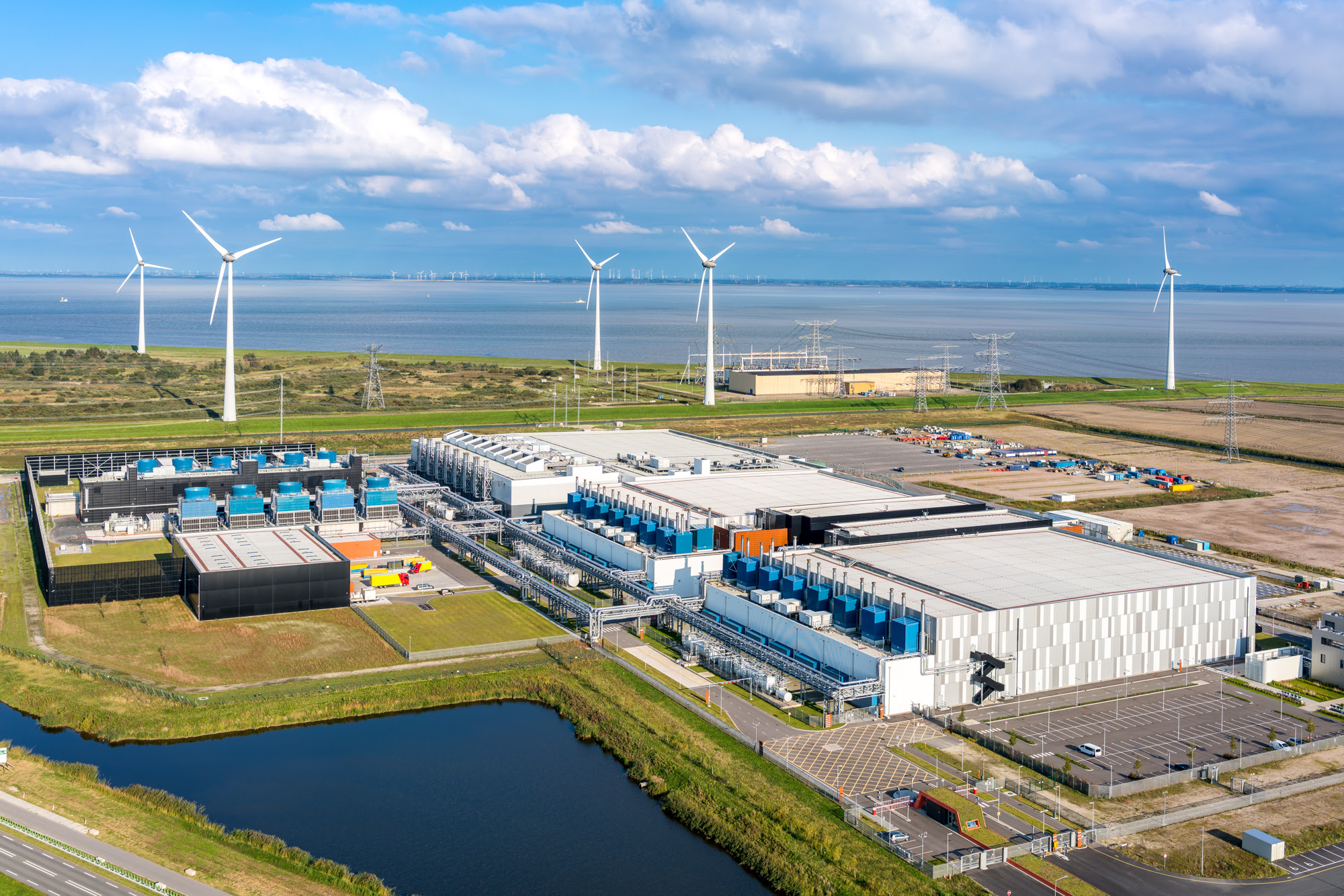 Aerial view of a Google data centre campus, with cooling plants and wind turbines nearby